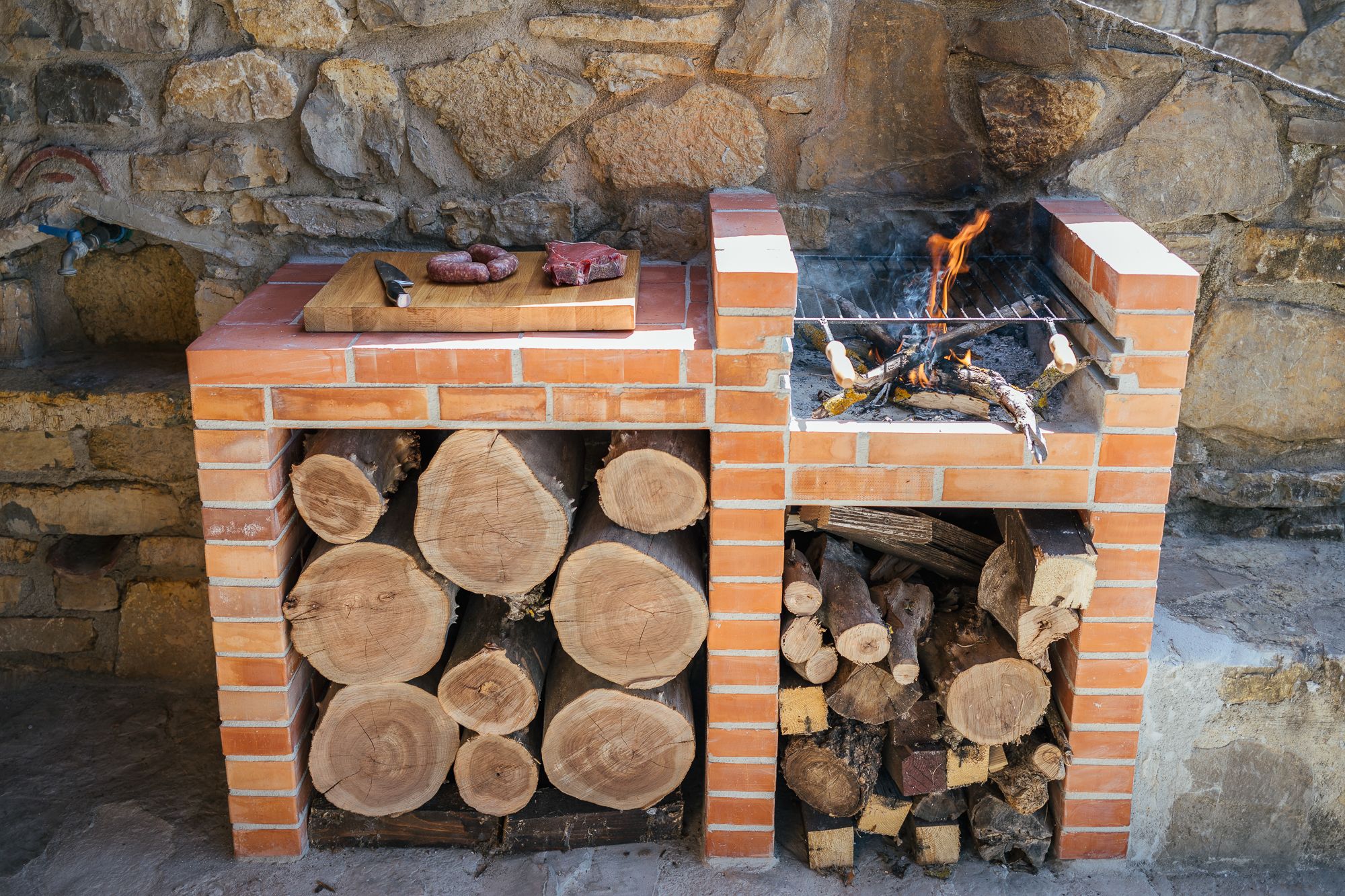 Outdoor kitchen of stone and brick with its stacked firewood