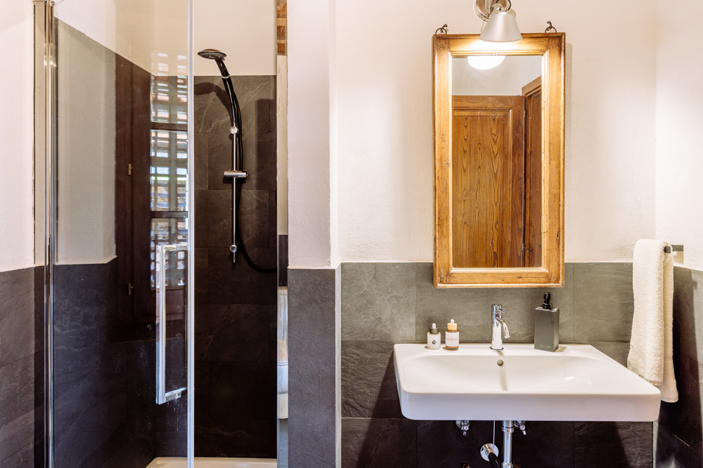 Badezimmer mit Schiefer-Dusche, Waschbecken und Holzspiegel