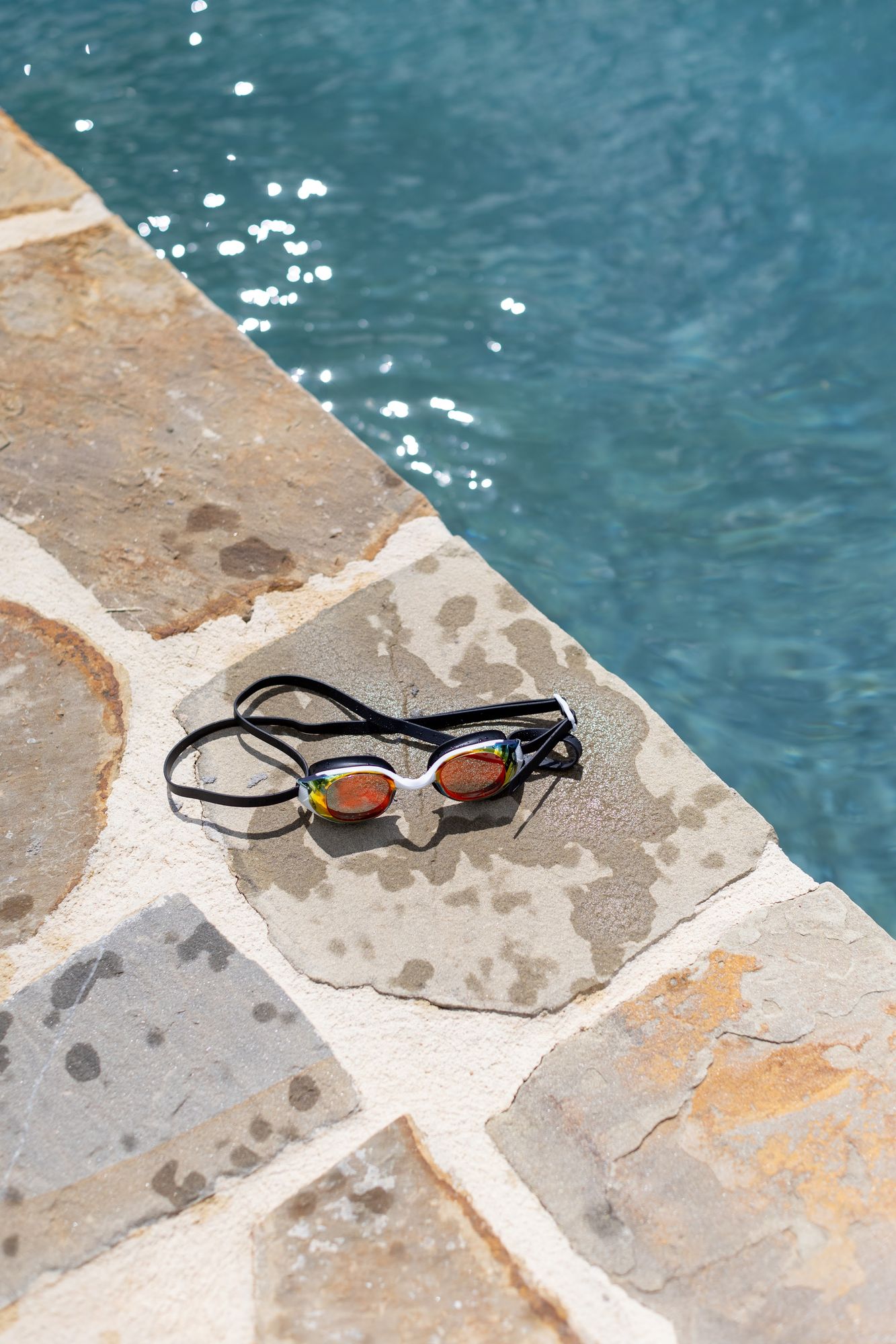 Swimming goggles on the warm stone at the edge of the pool