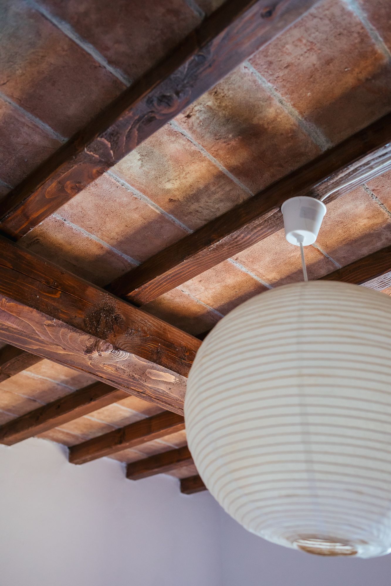 Paper lantern hanging beneath the terracotta roof beams