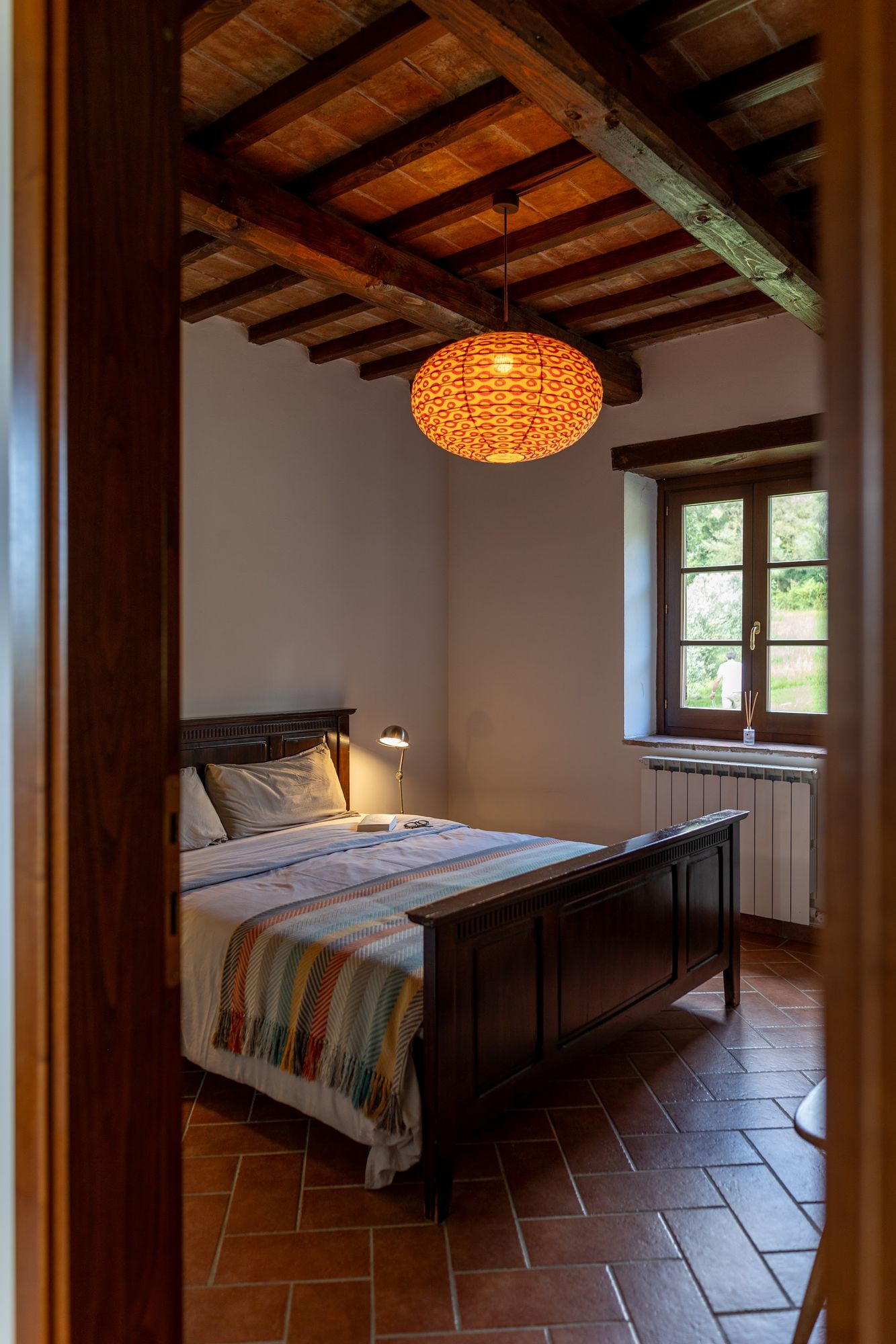 Bedroom under a beamed ceiling with a window onto the countryside